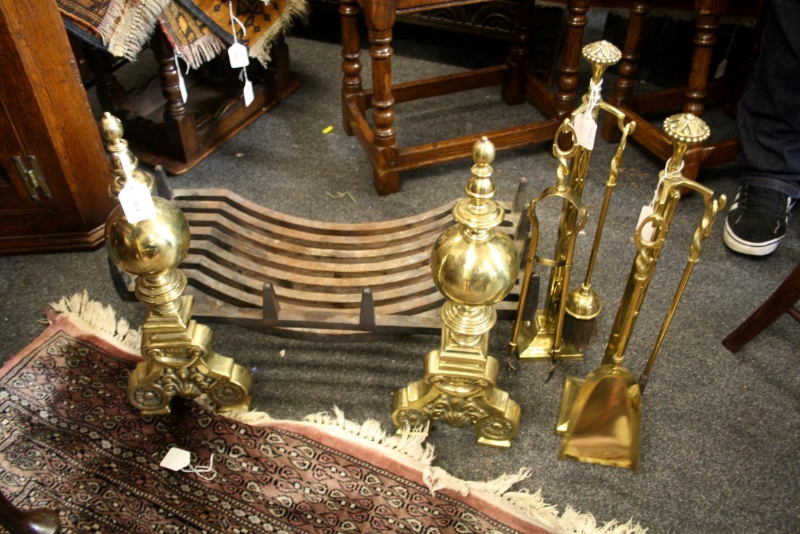 A pair of 19th century steel and brass fire dogs with spherical shafts on scrolled florally cast