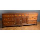 A good George III oak low dresser, the mahogany crossbanded top with a moulded edge over eight