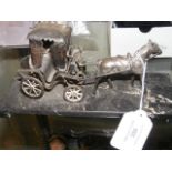 A white metal ornament of horse and carriage