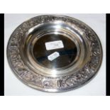 A white metal dish with repousse decoration to the