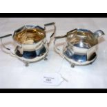 A silver cream jug with the matching sugar bowl