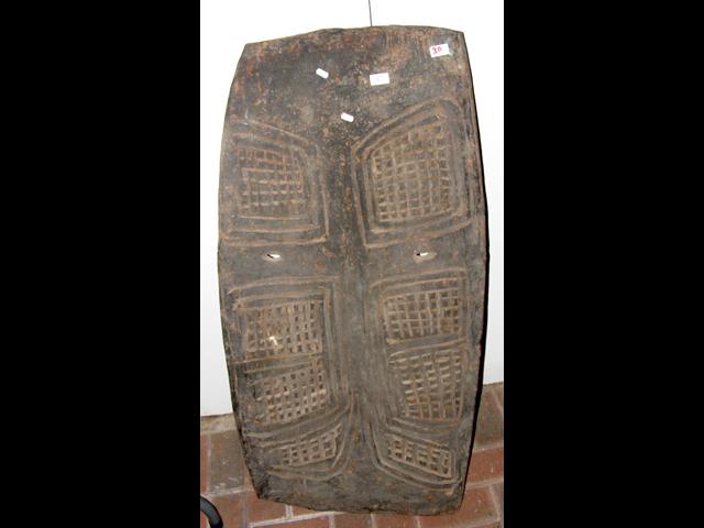 A carved wooden war shield with geometric decorati