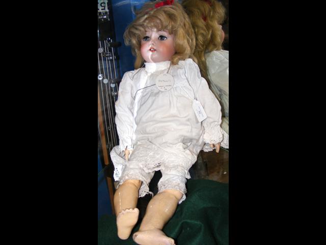 An antique bisque head doll with glass eyes and co