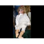 An antique bisque head doll with glass eyes and co