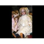 A large antique bisque head doll with glass eyes a