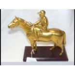A gilt bronze model racehorse and jockey on wooden