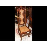 An antique hall chair with carved backrest and can