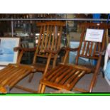 A pair of vintage folding steamer chairs with carv