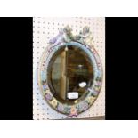 A 32cm flower encrusted wall mirror with cherub mo