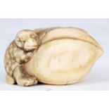 A JAPANESE IVORY SCULPTURE of a monkey holding a large nut.