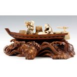 A JAPANESE MEIJI PERIOD CARVED IVORY AND ROSEWOOD SCULPTURE MODELLED AS A FISHING BOAT AT SEA having