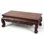 A 19TH CENTURY CHINESE HARDWOOD LOW OCCASIONAL TABLE with panelled top and shaped scroll carved base