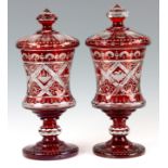 A LARGE PAIR OF LATE 19TH CENTURY BOHEMIAN RUBY GLASS URNS AND COVERS with cut glass and etched