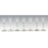 A SET OF SEVEN 18TH/19TH CENTURY WINE GLASSES with tulip shaped vessels, bulbous barley twist