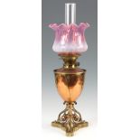 A LATE VICTORIAN GOTHIC STYLE COPPER AND BRASS OIL LAMP with stylised base and pink vaseline