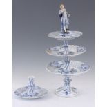 A MEISSEN BLUE AND WHITE PORCELAIN THREE TIER CAKE STAND WITH FIGURAL TOP with graduated latticework