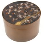 A MEIJI PERIOD JAPANESE PATINATED BRONZE LIDDED CYLINDRICAL BOX with mixed metal panel depicting a