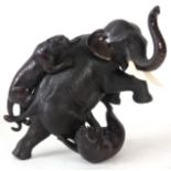 A JAPANESE MEIJI PERIOD PATINATED BRONZE SCULPTURE formed as an elephant fending off two tigers,