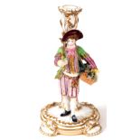 A 19TH CENTURY MINTON CANDLESTICK on a white ground with gilt decoration, supporting a figure of a