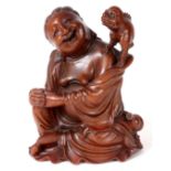 A LATE 19TH CENTURY CHINESE CARVED HARDWOOD FIGURE of a seated Buddha playing with a pig 25cm