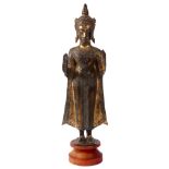 AN ANTIQUE TIBETAN GILT BRONZE STATUE OF A STANDING BUDDHA on a circular wooden base 47cm high.