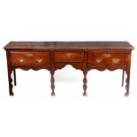 AN UNUSUAL MID 18TH CENTURY OAK SILHOUETTE LEGGED DRESSER BASE with moulded plank top above three ‘