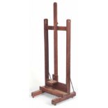 A LATE 19TH CENTURY / EARLY 20TH CENTURY OAK ADJUSTABLE EASEL with rack and pinion adjustable, under