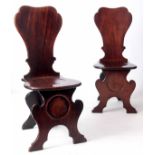 A PAIR OF GEORGE II MAHOGANY HALL CHAIRS OF RICH COLOUR AND PATINA the slightly bowed shaped solid