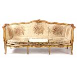 A 19TH CENTURY LOUIS XV STYLE GILT GESSO SERPENTINE SHAPED THREE SEATER SETTEE with flower carved