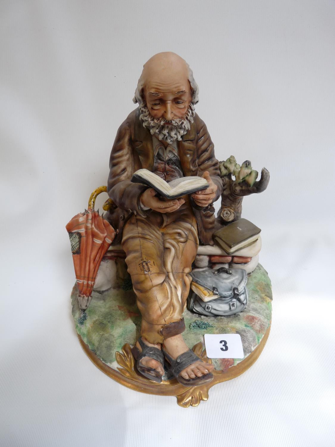 Capodimonte figure of a man on a brick wall reading a book with gilded detail, marked 108 to base,