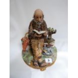 Capodimonte figure of a man on a brick wall reading a book with gilded detail, marked 108 to base,