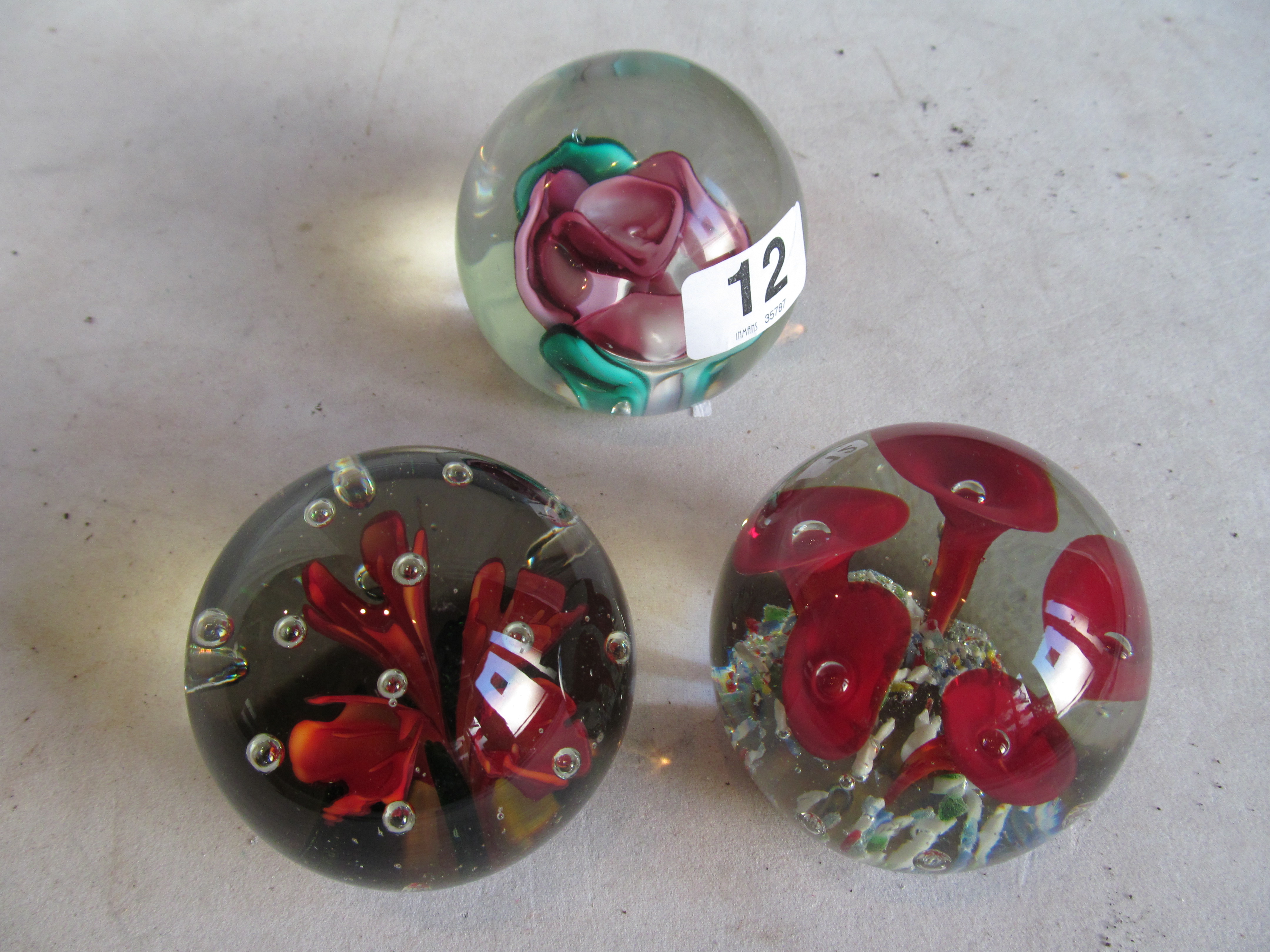 A lampwork paperweight and two flower paperweights.