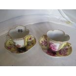 A Meissen style two handled chocolate cup and saucer with puce coloured reserves of cherubs, and