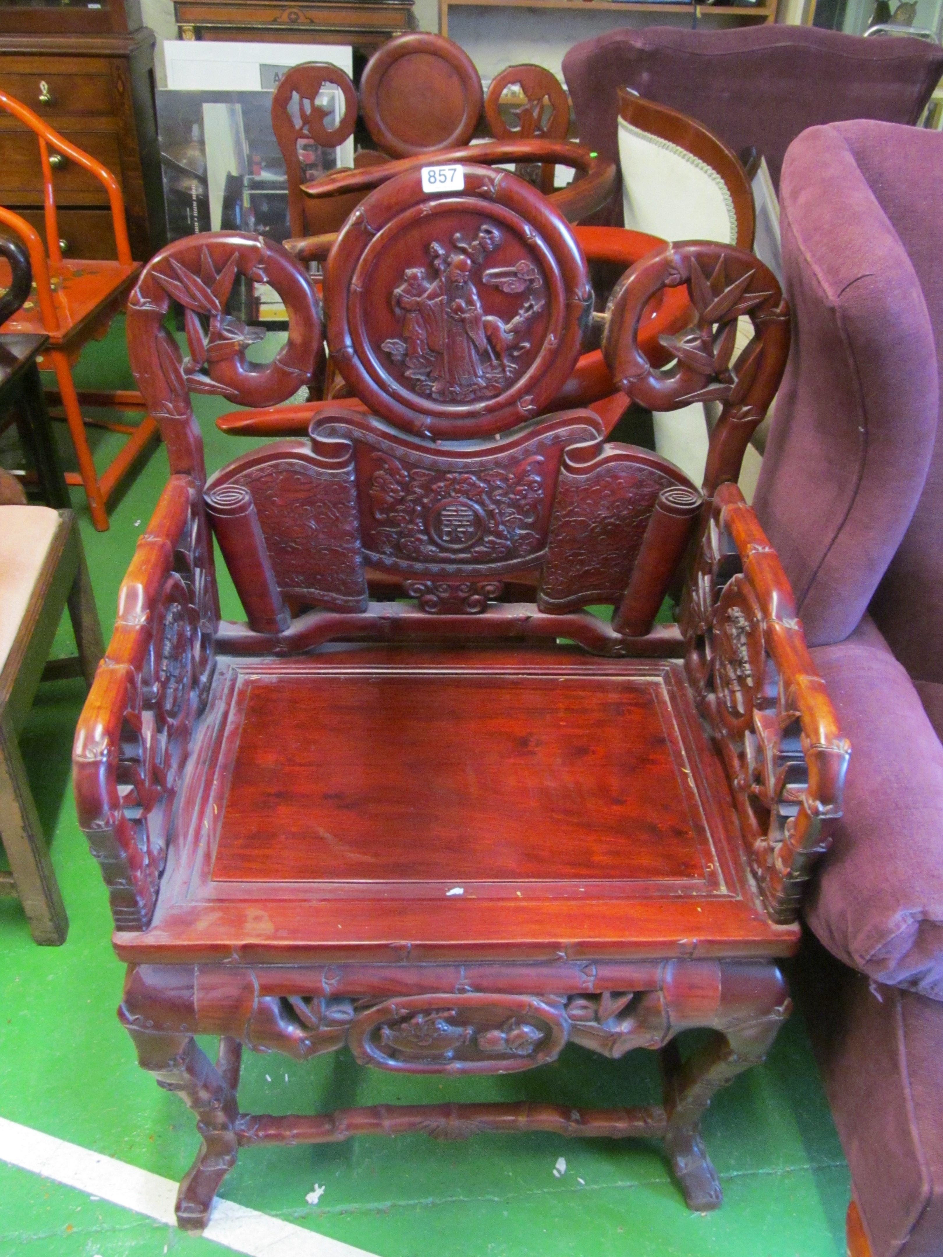 A pair of oriental hardwood chairs with ornately carved back of bamboo design and figures