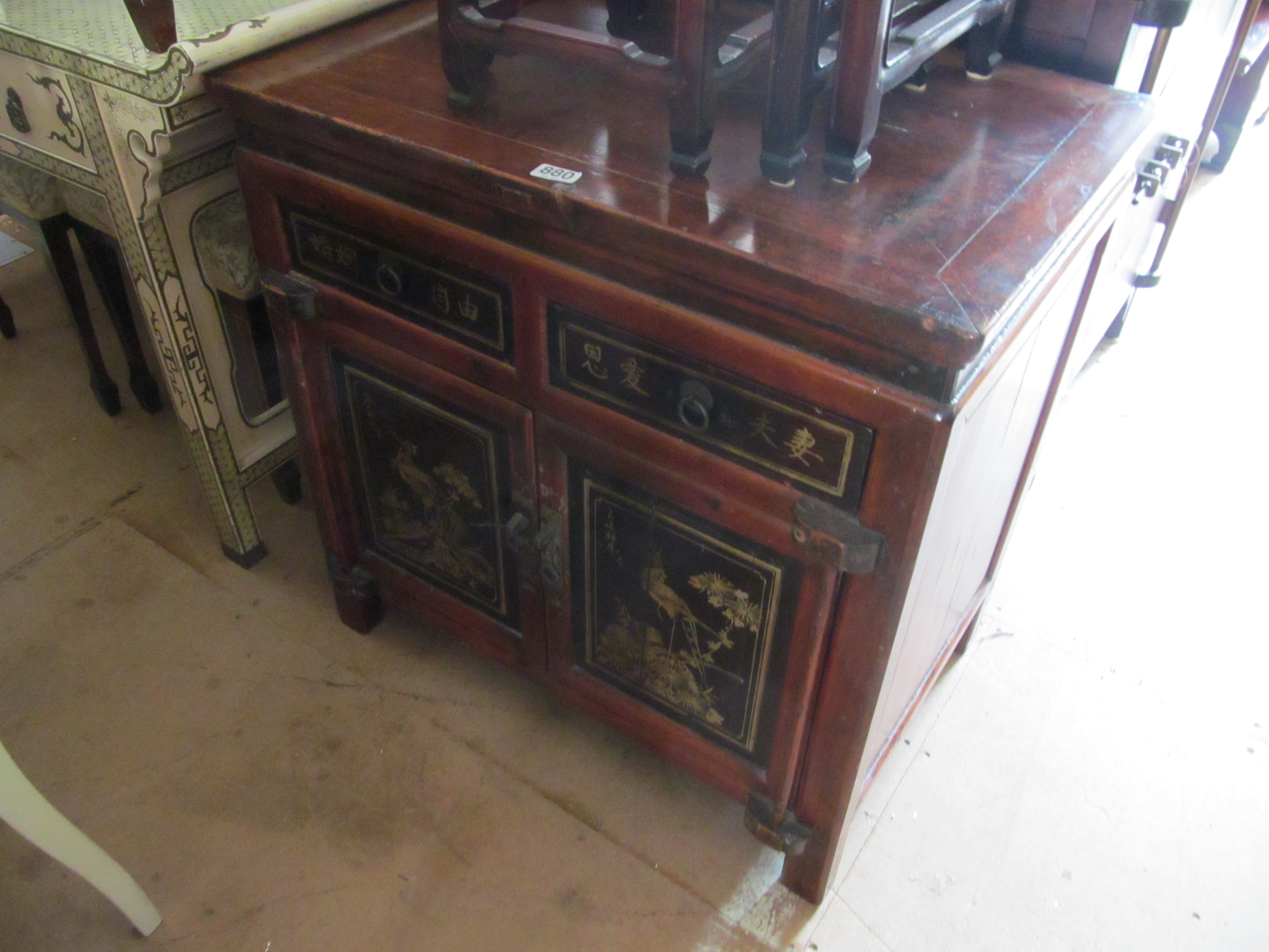 An oriental small two door cabinet with two drawers and lacquer panels
