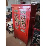An oriental red lacquer and gilt cabinet with pierced doors carved geisha