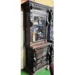 A carved oak bookcase with drawer and cabinet over