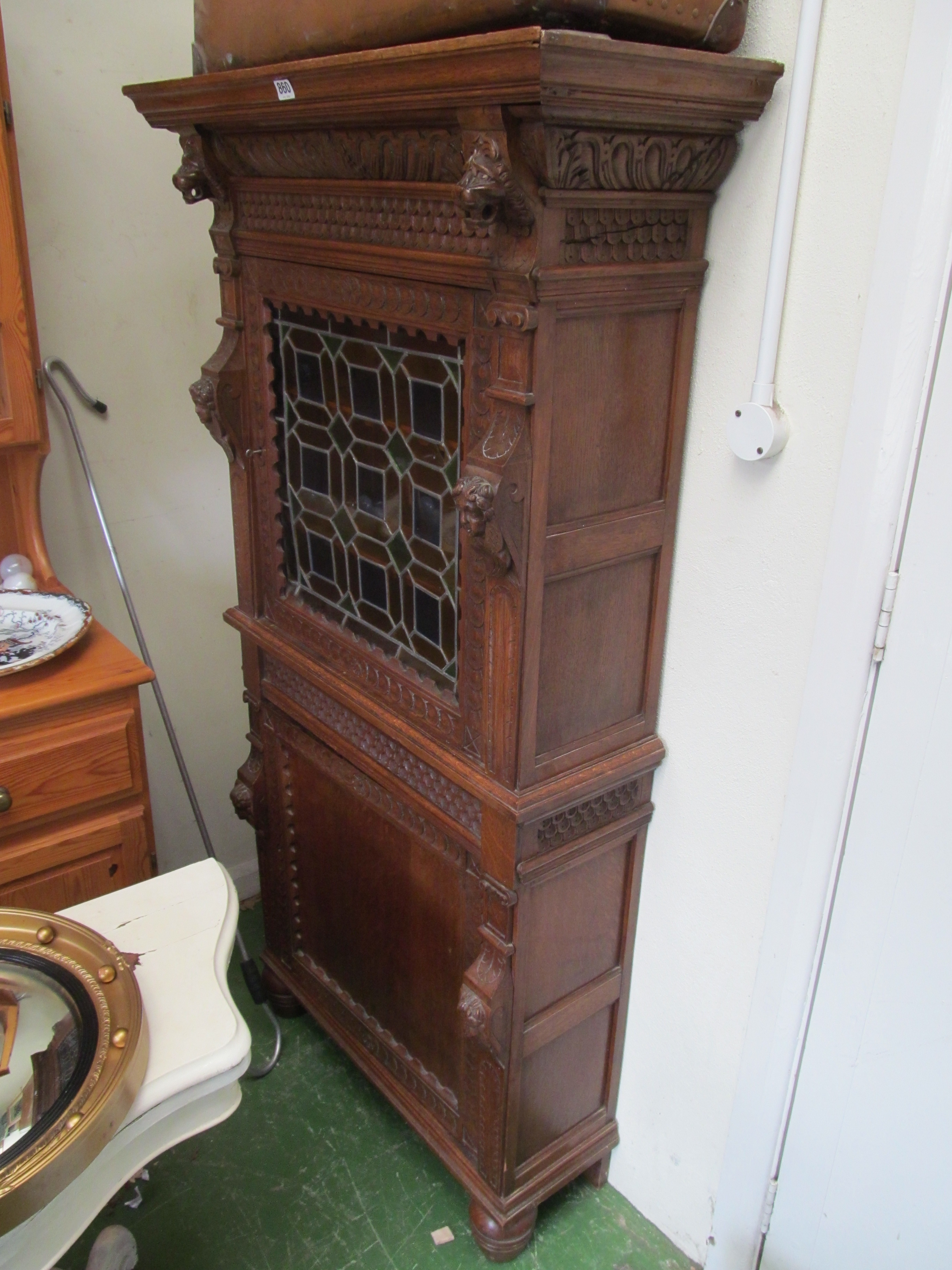 A continental oak cabinet with carved decoration, stained glass upper door and panelled door