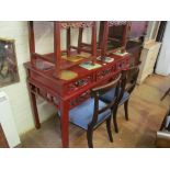 An oriental red lacquer sideboard with three drawers and carved frieze of figures