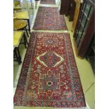 A madder ground rug with cream an blue stylized floral design and another similar
