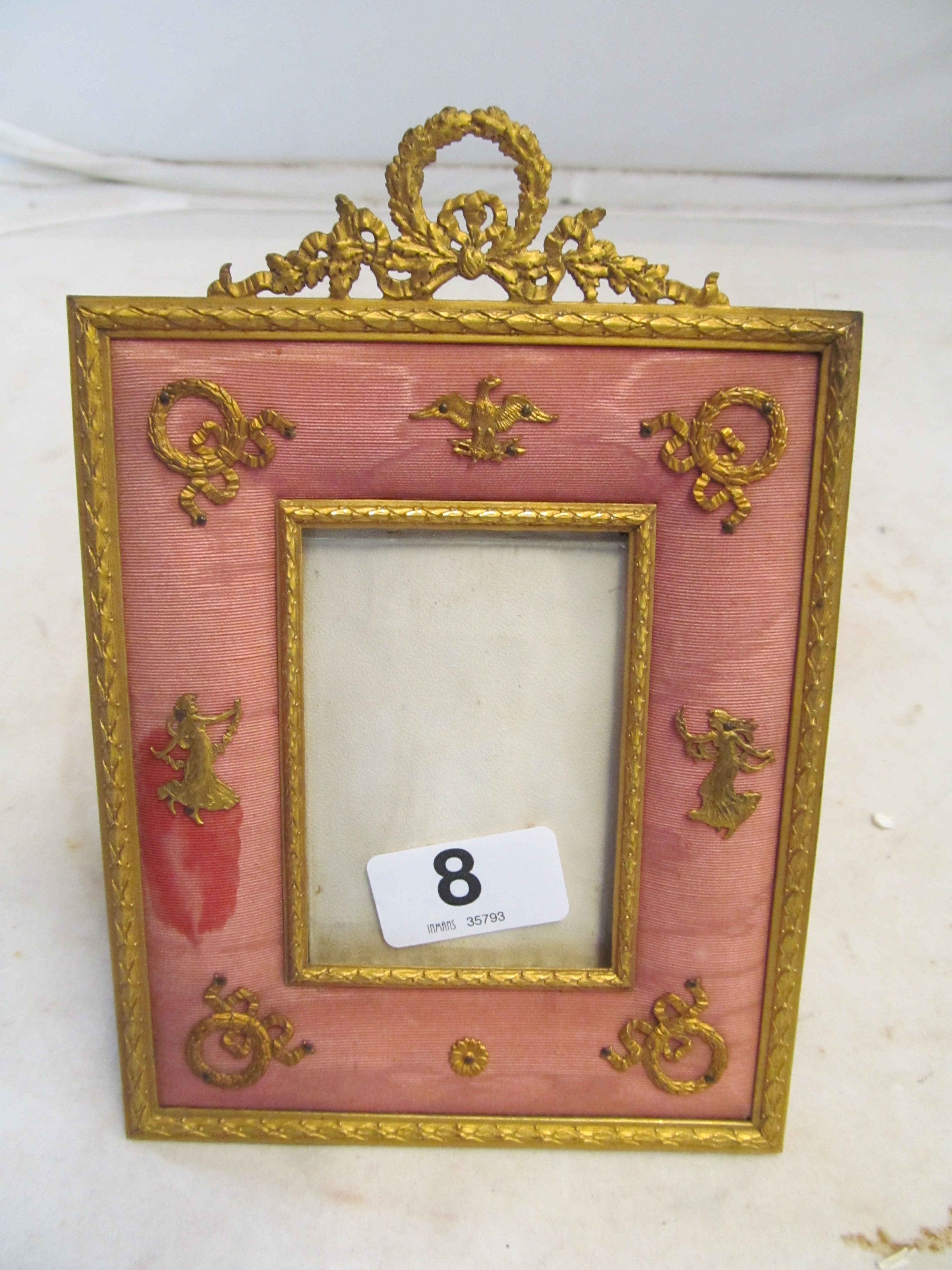 A small gilt photo frame with cushion frame applied gilt wreaths and classical motifs, retailed