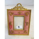 A small gilt photo frame with cushion frame applied gilt wreaths and classical motifs, retailed