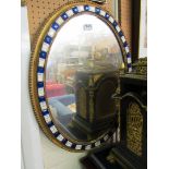 An oval mirror with blue and clear glass frame.