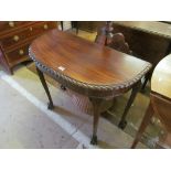 A mahogany demi-lune table with gadrooned border on cabriole legs, claw and ball feet