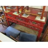 An oriental red lacquer sideboard with three drawers and carved frieze of figures