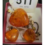 An amber coloured heart pendant on gold chain, pair of earrings and a heart pendant.