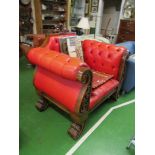 A large red leather button back armchair with exposed carved frame on scroll feet.