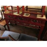 An oriental red lacquer sideboard with three drawers and carved frieze of figures