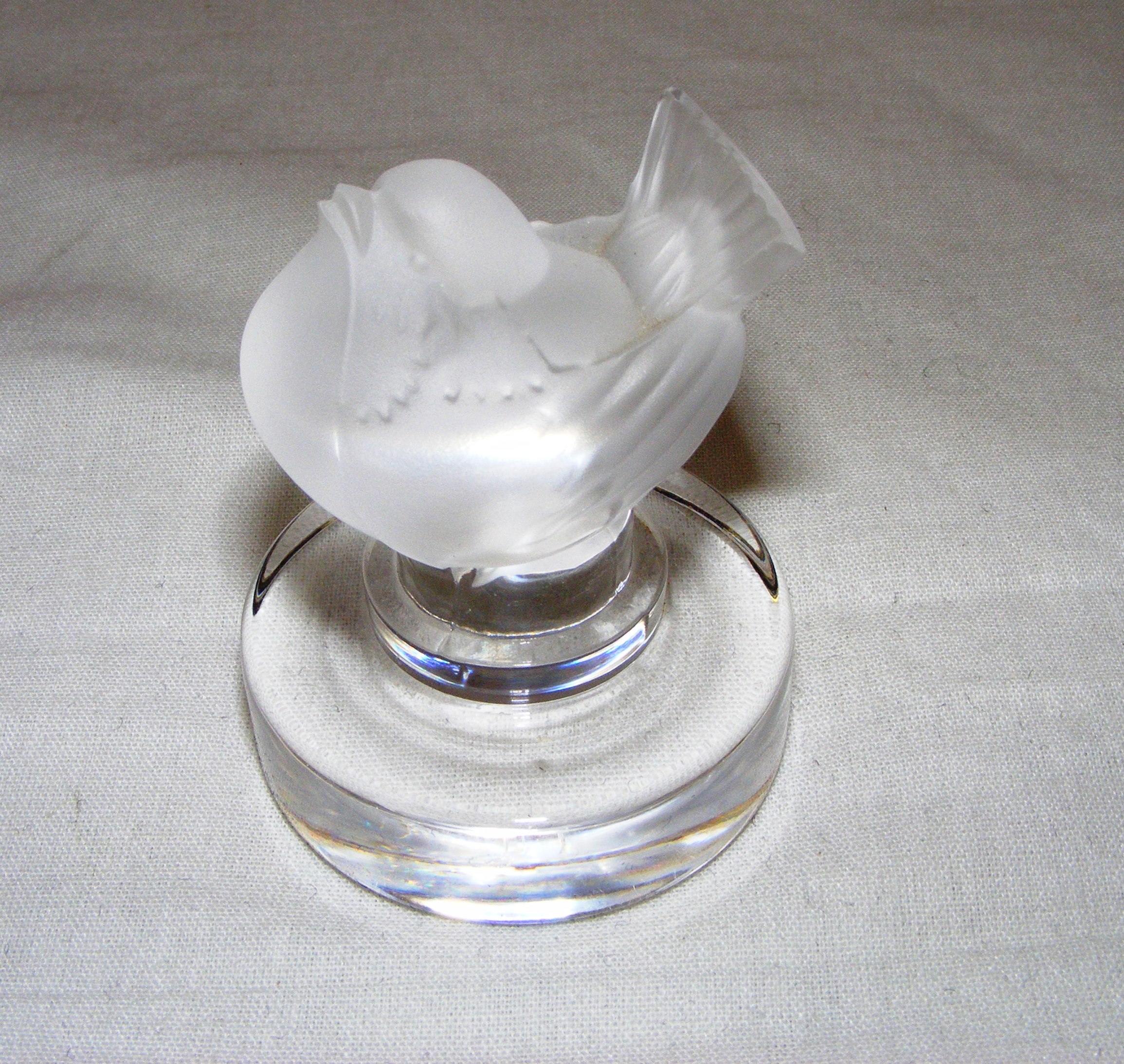 A Lalique frosted glass bird paperweight measuring 6cm tall and signed to the base.