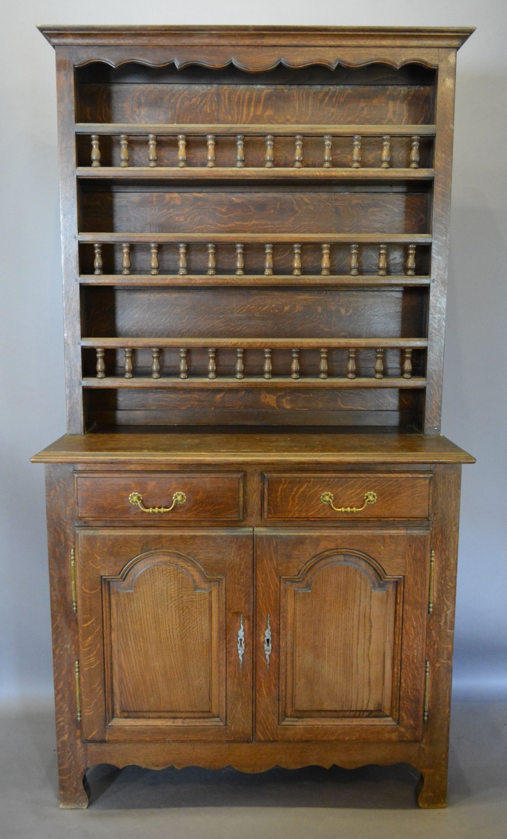 A French Oak Dresser, the boarded shelf back above two drawers and two arched cupboard doors,